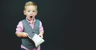 Staunender Bub mit Buch in der Hand